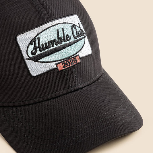 Black cap with 'Humble Club' logo on a beige background