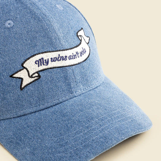 Blue denim cap with embroidered banner on a beige background